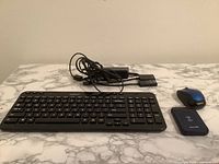 Photo of entire lot including Logitech wireless keyboard, wireless mouse, Merlin power bank, HP adapter and cables