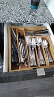 Opened drawer displaying organized 18/10 stainless steel flatware including knives, forks, spoons, and various utensils.