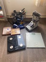 Photo showing medical walking boot, two digital scales, box with assorted grooming tools including wooden brushes and hair styling irons.