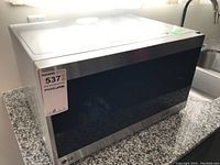 Full view of LG microwave on granite countertop from left side, showing stainless steel body and black glass door.
