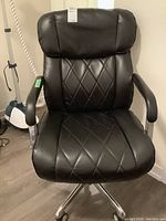 Full front view of chair showing seat, backrest, armrests and chrome base