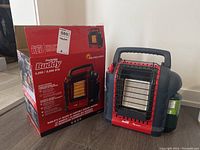 Photo of the Buddy Red Portable Buddy propane heater with its original box. Shows front and side of the heater and box branding.
