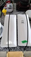 Top view of two white rectangular serving dishes tied together with elastic bands.