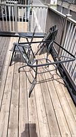 Patio chairs and table frame set on wooden deck showing folding mesh chairs and steel table base.