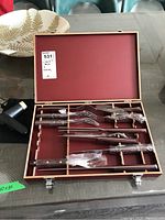 Full view of wooden storage box open with carving utensils and cooking torch on table