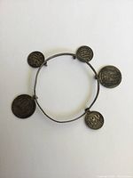 Full view of the antique sterling silver coin bracelet with five etched monogrammed coins on a white background.