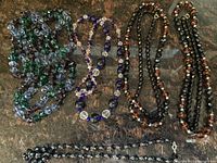 Four faceted bead necklaces laid out on a surface, showing different colors and lengths.