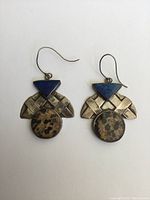 Pair of silver drop earrings with blue triangular lapis stones and round spotted brown agate stones, waffle-patterned silver detail.