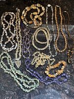 Overhead photo showing the entire group lot of natural stone and faceted crystal necklaces and bracelet with various colors, beads, and pendants.