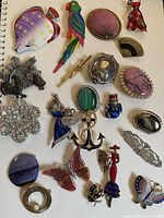 Photo of assorted vintage brooches in various materials and colors spread on a surface