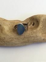 Front view of silver ring displaying irregular shaped blue opal stone set in bezel.