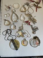 Image showing an assortment of clear faceted crystals, various pendants including butterfly and star shapes, dragonfly brooch, and multiple necklaces.