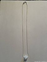 Full length view of the silver necklace with pendant showing overall shape and length.