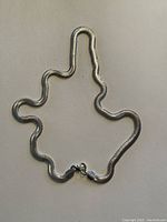 Photo showing silver necklace arranged with some curvature to display flexibility and shine.