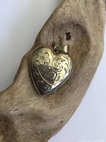 Front view of the heart-shaped sterling silver locket showing etched floral and swirl pattern.