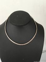 Front view of the sterling silver choker necklace displayed on a black stand showing textured chain design and circular shape.