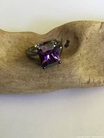 Front angle of the sterling silver ring showing the large purple emerald cut crystal center stone, tarnish and surface wear visible.