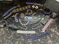Photo showing assortment of vintage rhinestone bracelets, necklaces and cuff bracelets arranged on a dark surface.
