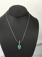 Full view of necklace on black bust showing drop pendant and chain length.