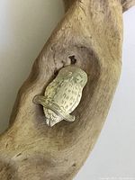 Front view of sterling silver hand-etched owl brooch placed on wood for texture.
