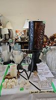 Wide view of assorted candle holders, flameless candles, tealights, and tin lanterns on a table with green tape markings
