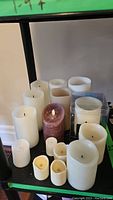 Shelf with assorted pillar candles showing cream, white, and brown colors and different sizes