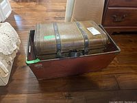 Photo shows the vintage wood chest inside the large red metal NVF Industries bin on a wooden floor.