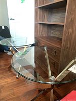Two matching glass top tables with metal bases. Round clear glass tops and modern intersecting metal strip bases.
