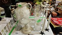 Overview of pottery jug, glass trio candleholders, metal and flameless candlesticks, glass deer candleholders on table