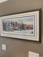 Framed print showing a winter street scene with houses and trees