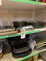 Shelves of cookware including casserole dishes with lids, baking pans, and roasting pans