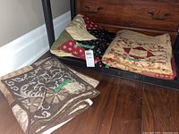 Four quilts folded and stacked on a metal shelf, showing various patterns and colors.