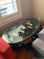 Oval coffee table top with glass surface showing painted Asian figures and motifs