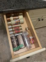 Drawer with assorted bottles of room sprays and holders for bath or body products.