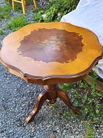 Full side view of the antique 1920s wooden pedestal side table showing the pedestal base and wood inlay on tabletop.
