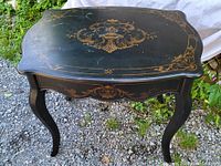 Full view of black lacquered wood side table showing curved legs and scalloped edges.