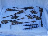 Full overview of all iron curtain rods, finials, and hooks arranged on fabric background showing ornate designs and painted details.