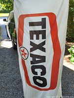 Photo of full white nylon Texaco flag held outdoors with visible red border and black text, slight fraying