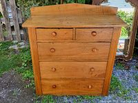 Front view of chest showing five drawers and backsplash