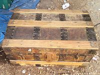 Top view of the small steamer trunk showing wooden slats and metal banding across the domed lid.