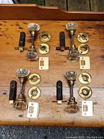 Full view of all four door knob sets laid out on wooden surface with corresponding hardware including latch bolts, brass rose plates, and strike plates.