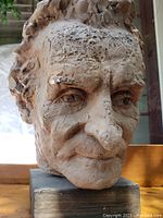 Close-up front-left angle showing facial features, texture and pine base.