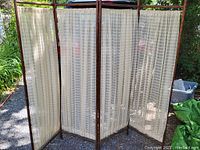 Four-panel Victorian oak room screen photographed outdoors with visible old fabric with subtle checked pattern.