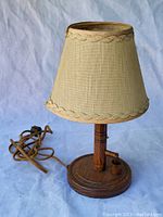 Photo of the full lamp showing the oak wood base and beige fabric lamp shade with trim.