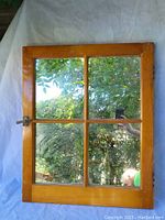 Front view showing the entire pine framed window with four mirrors reflecting greenery and outdoor scenery.