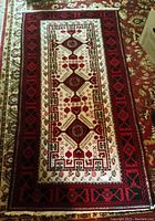 Full view of rectangular hand-woven wool rug showing overall pattern and colors on floor.