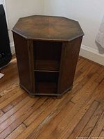 Front view of the octagonal wooden bar storage cabinet showing top surface and interior shelf.