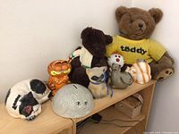 Full lot showing two teddy bears, ceramic cat figurines including Garfield, a white spotted dog, a gray round cat face, and an orange and white cat figurine along with a red and white clown figurine.