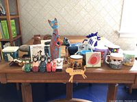 Wide shot of the entire collection on a wooden table showing multiple cat and bird-themed decorative items including figurines and mugs.