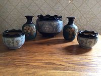 Group photo of five ceramic items: two vases and three bowls with floral designs and dark blue ruffled rims.